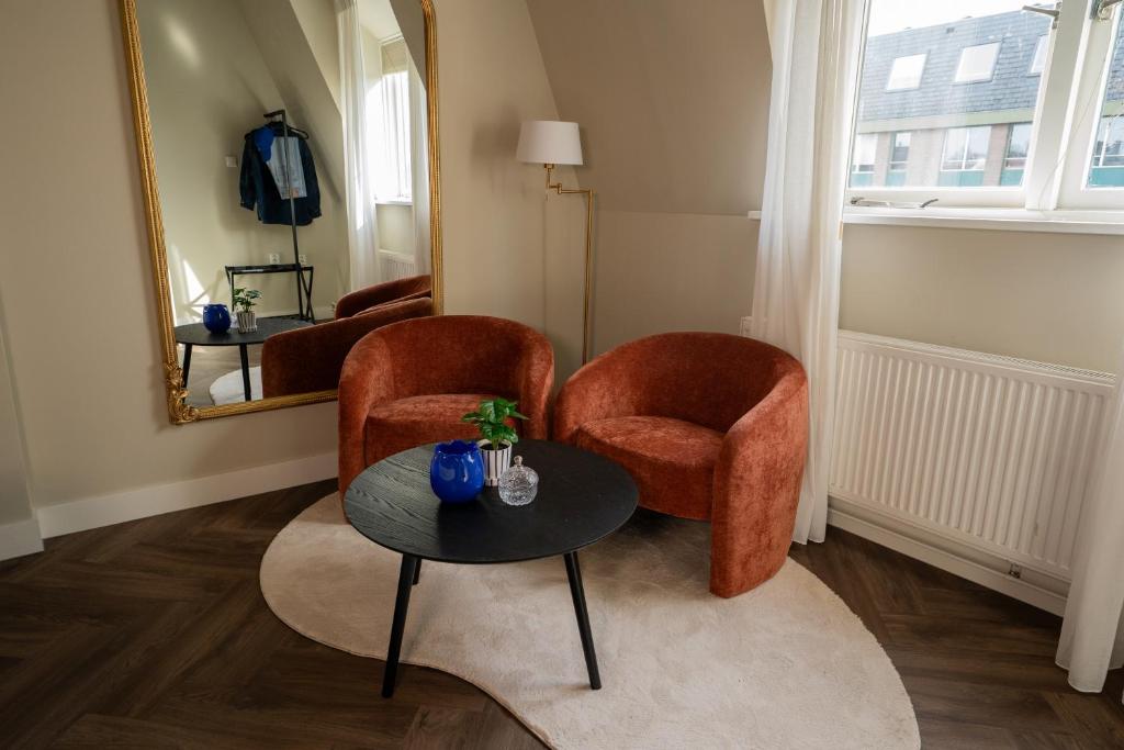 a room with two chairs and a table and a mirror at Boutique Hotel By Atelier in Nijmegen