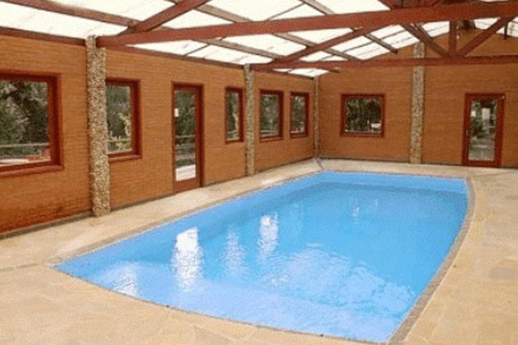 a large blue swimming pool in a building at Hotel Pião Mineiro in Monte Verde