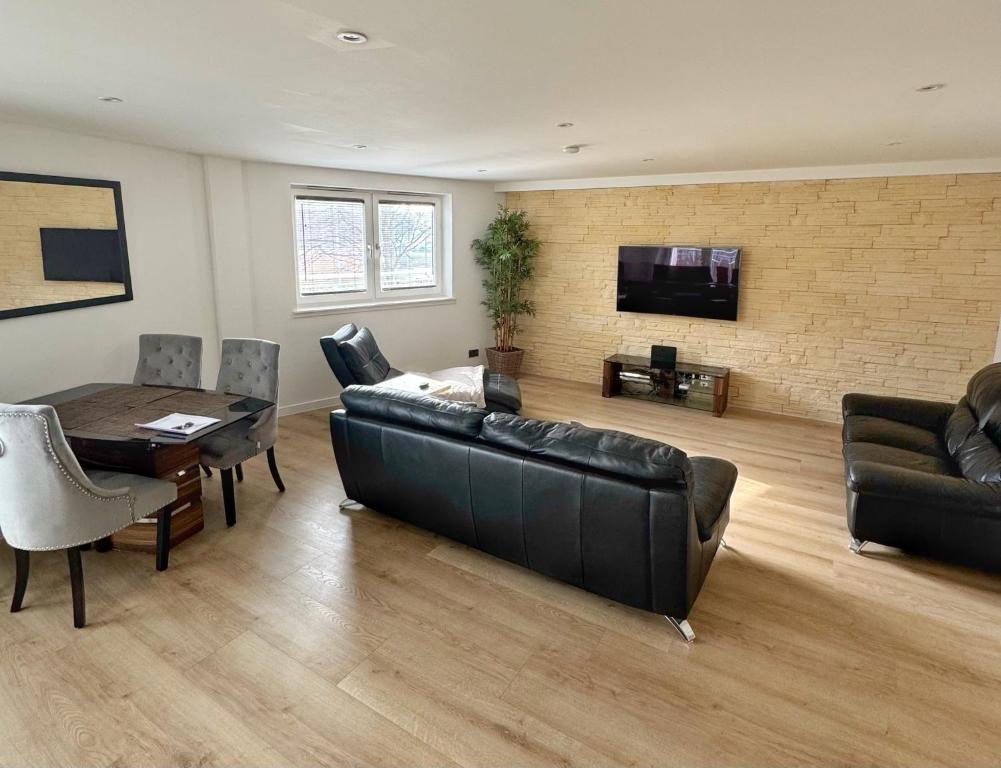 a living room with a black leather couch and a table at KM Granton Apartment in Edinburgh