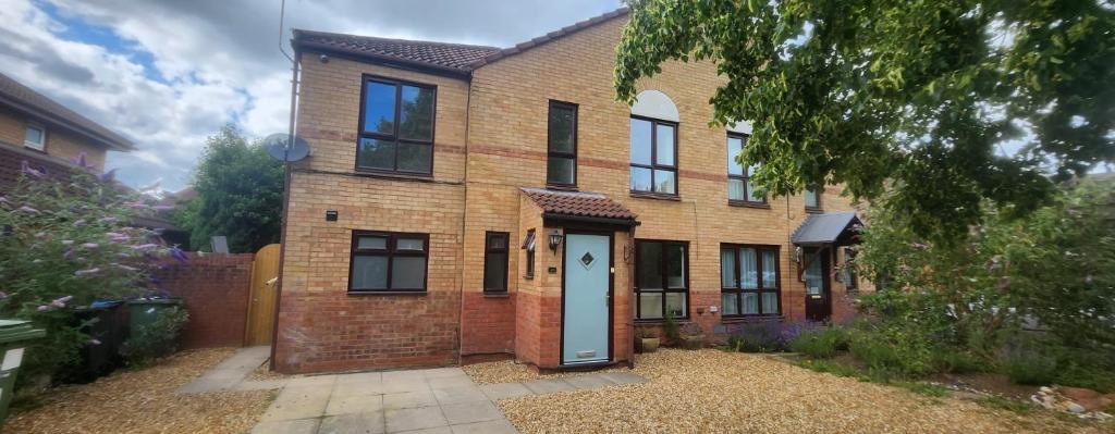 a brick house with a white door in a yard at 4 Bed 3 Bath Dryer Sky TV & Netflix Free Parking Rear Garden Prime Location in Willen