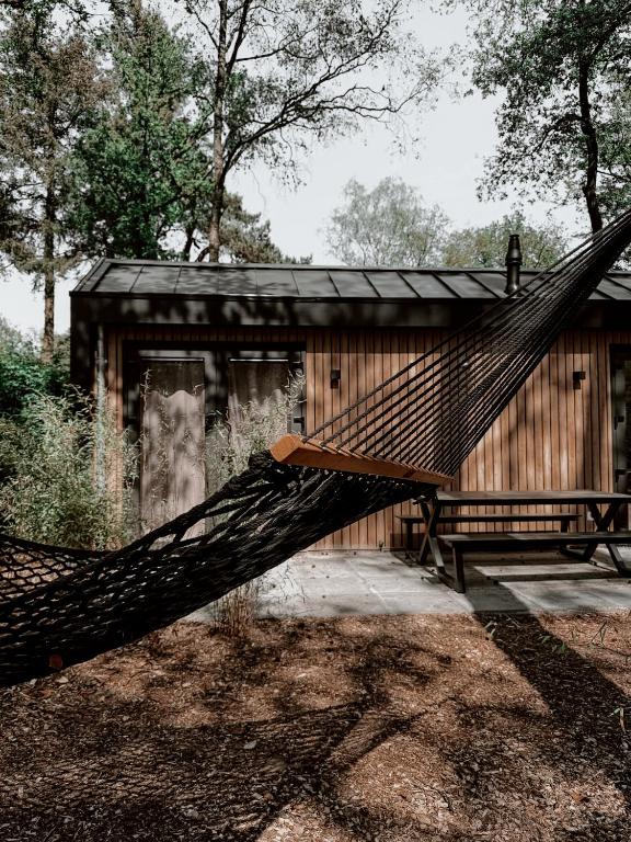 a hammock in front of a wooden building at Casa Mundo in Nunspeet