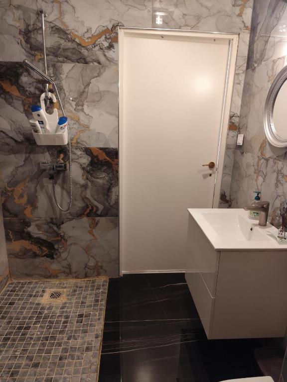 une salle de bain avec un lavabo blanc et une douche dans l'établissement Appartement Confort avec parkings gratuits, à Andolsheim