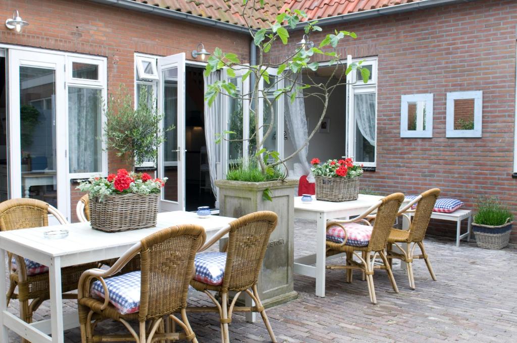 een groep tafels en stoelen met bloemen op een patio bij Hotel Steeds aan Zee in Katwijk