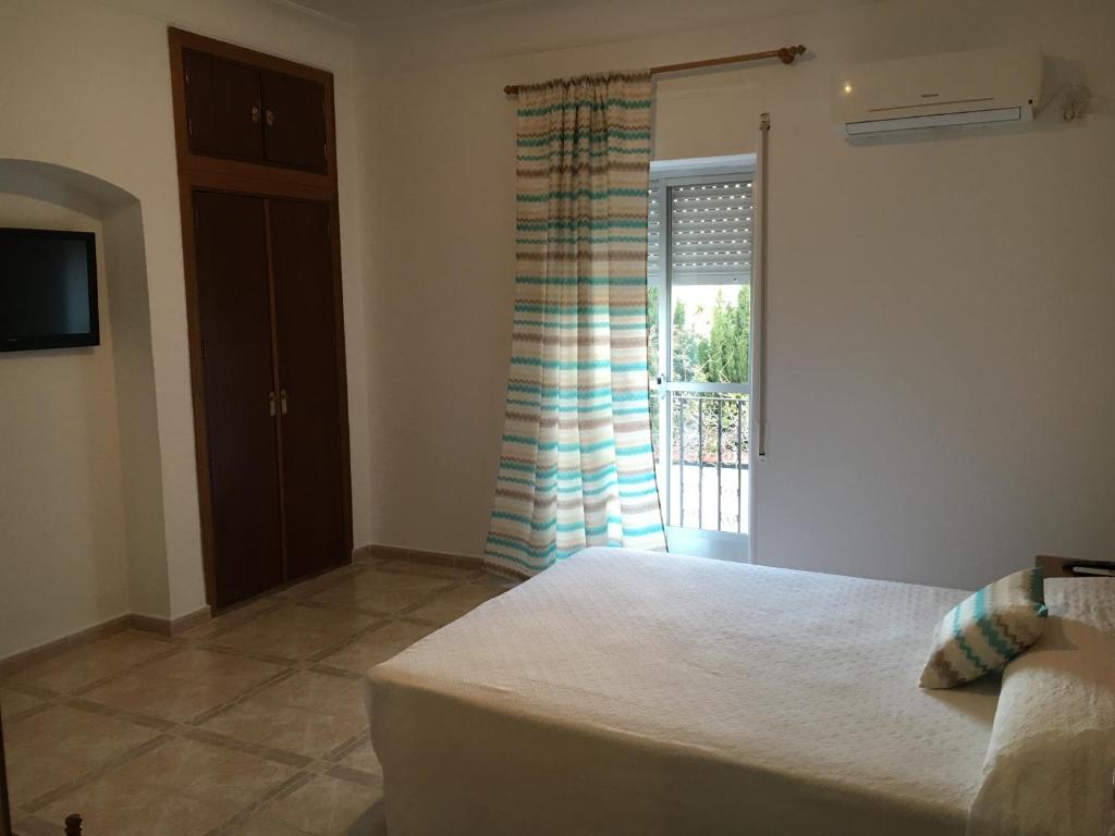 a bedroom with a bed and a window with a curtain at Hostal Barbate in Barbate