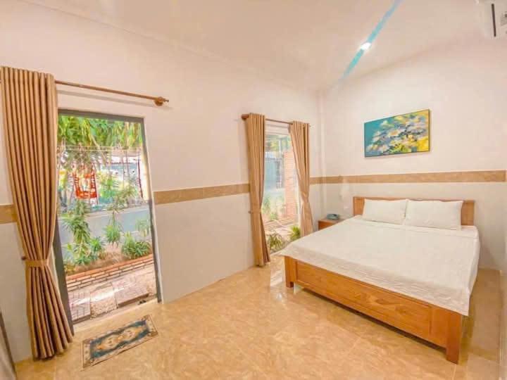 a bedroom with a bed and a large window at Đạt Ngọc Hotel in Ấp Thiện Long