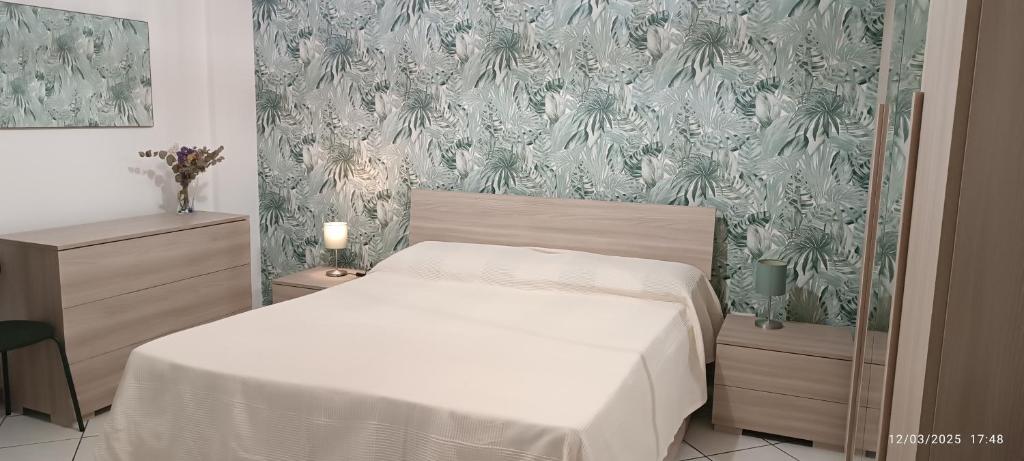 ein Schlafzimmer mit einem weißen Bett und einer Blumentapete in der Unterkunft Casa A Pupidda vicino al mare in Avola
