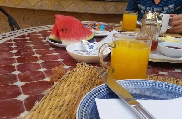 a table with a plate of food and a glass of orange juice at Dar Menorca in Merzouga