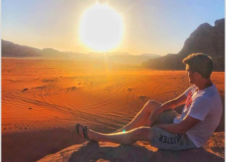 ワディ・ラムにあるMars moon campの夕暮れのビーチに座っている若い男性