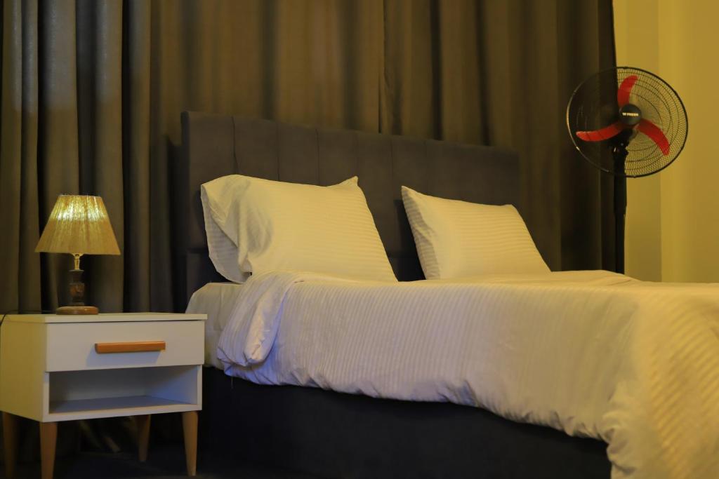 a bedroom with a bed with white sheets and a fan at Studio in the heart of Cairo in Cairo