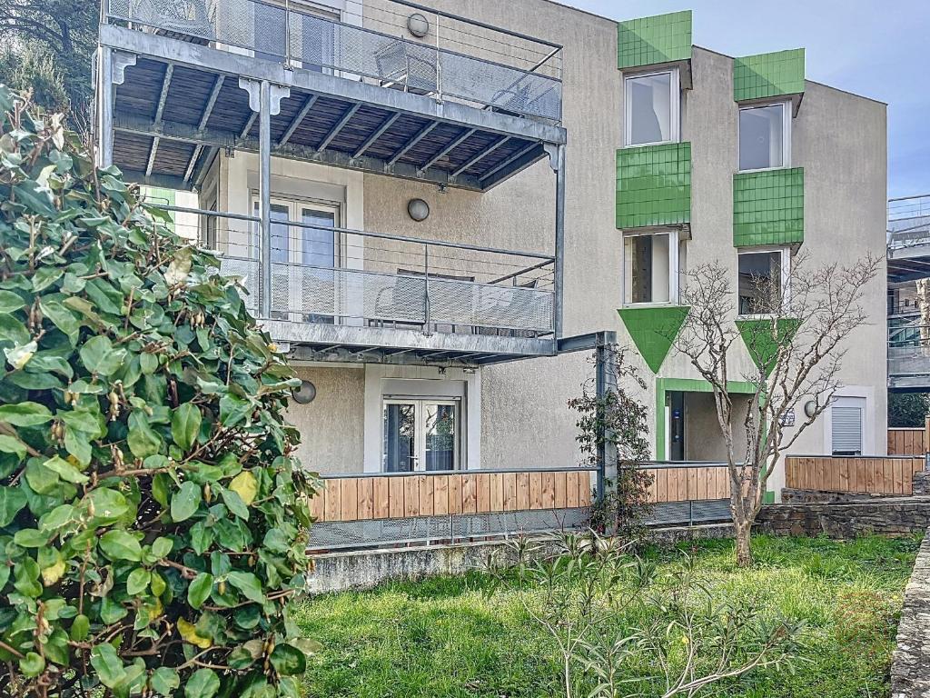 un immeuble d'appartements avec un balcon et un arbre dans l'établissement Studio rénové avec terrasse, proche des Thermes et du centre ville, Lamalou-les-Bains - FR-1-451-61, à Lamalou-les-Bains