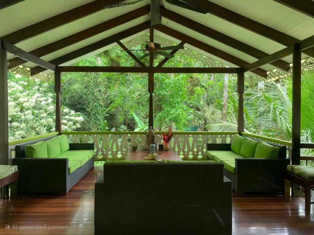 una sala de estar con sofás verdes en una terraza de madera en Pimienta Negra House, en Talamanca