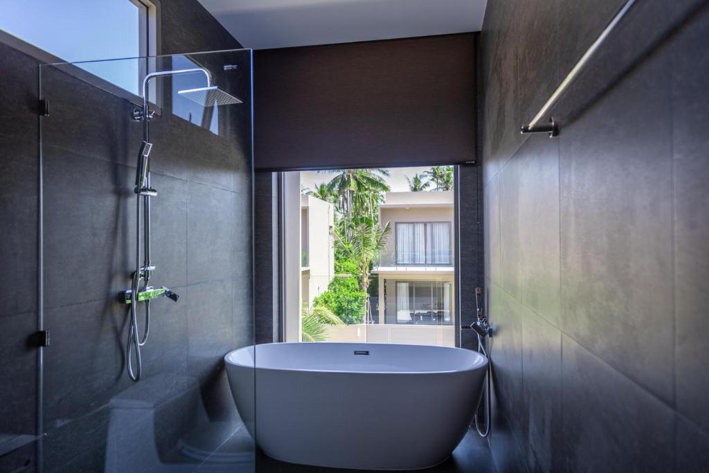 una bañera en un baño con ventana en 3 Bed Pool Villa Near The Beach - KBR29, en Ban Tai