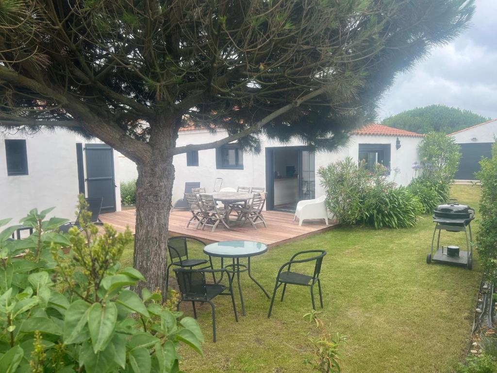 un patio avec des chaises, une table et un arbre dans l'établissement Maison rénovée au calme, proche plage & commerces, Noirmoutier, 4 pers. - FR-1-823-1, à Noirmoutier-en-l'lle