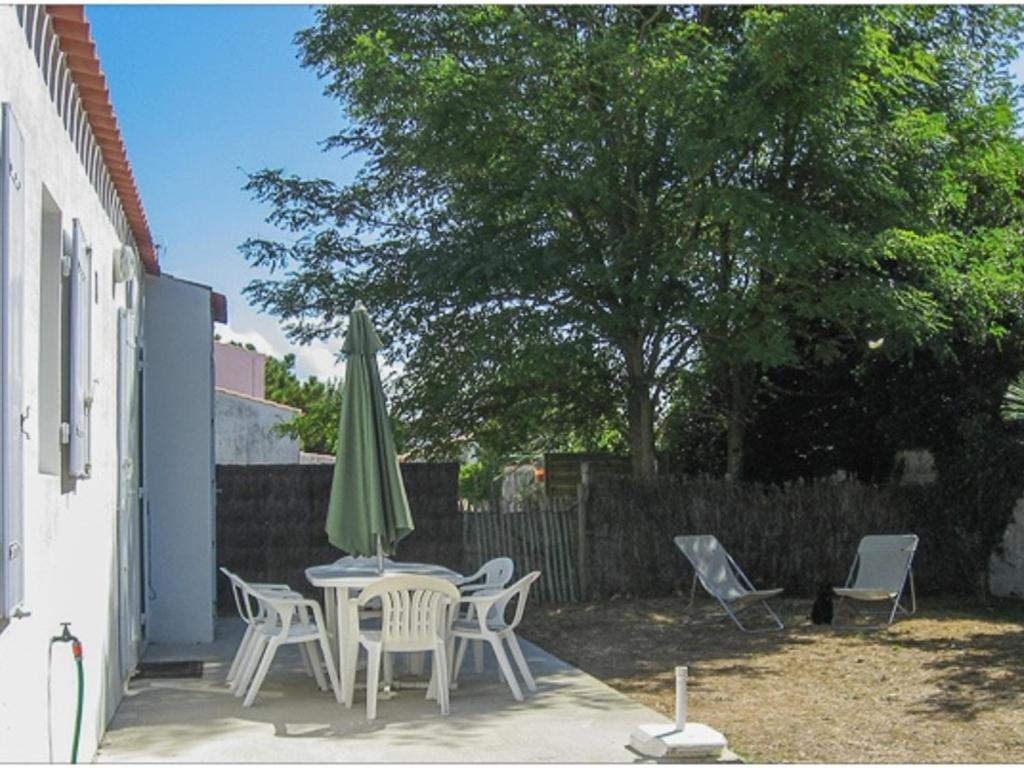 une terrasse avec une table, un parasol vert et des chaises dans l'établissement Maison 4/6 personnes à L'Épine avec animaux admis et jardin clos - FR-1-823-8, à LʼÉpine