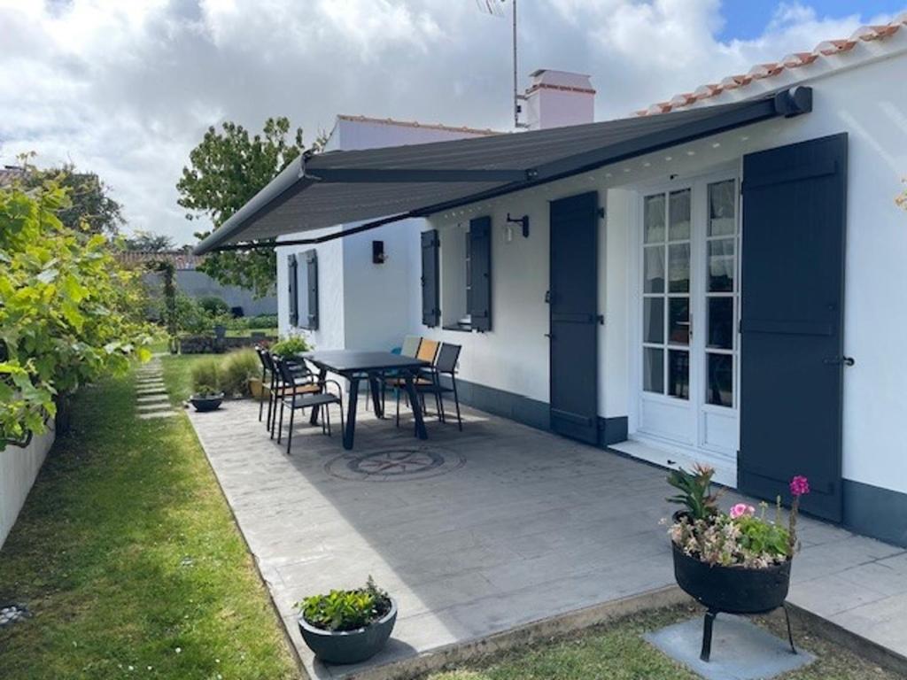une maison avec un patio avec une table et des chaises dans l'établissement Maison Confortable Noirmoutier pour 6 Pers, Jardin Clôturé - FR-1-823-11, à Barbâtre