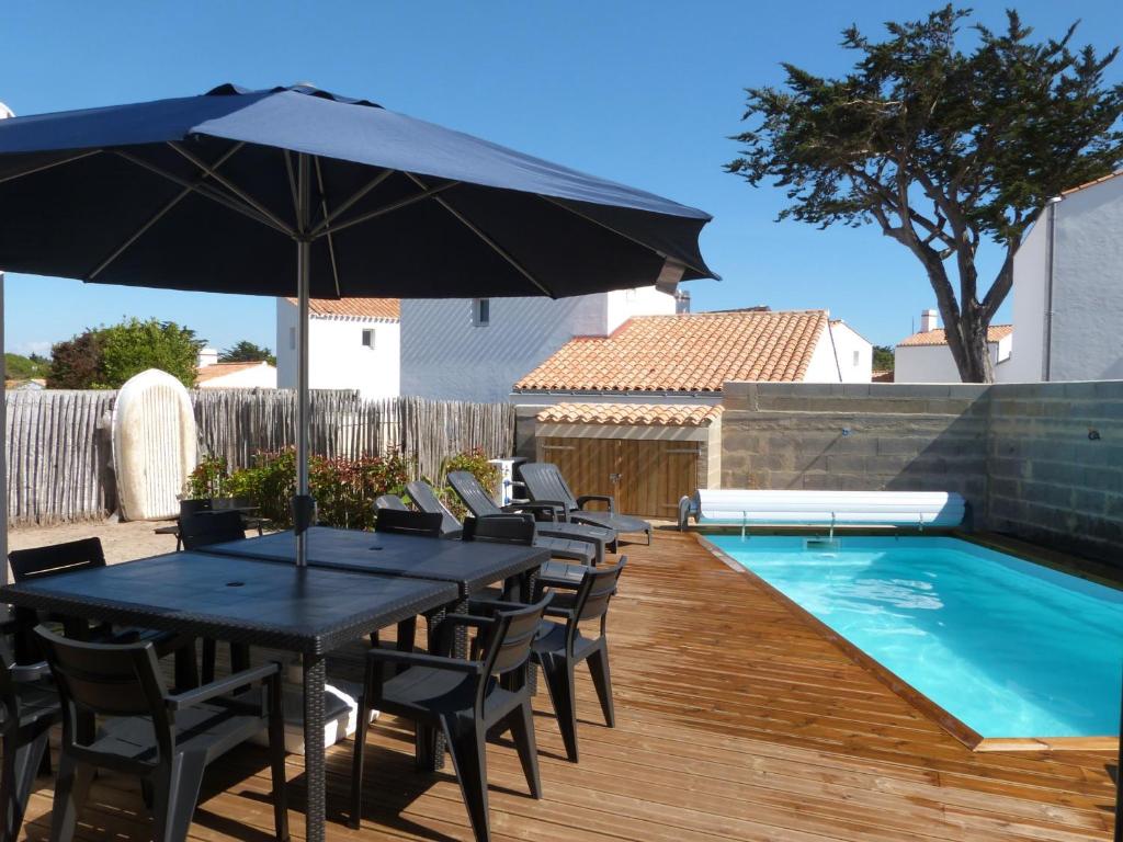 - une table avec un parasol à côté de la piscine dans l'établissement Maison neuve avec piscine privative à Noirmoutier - 10 personnes - FR-1-823-28, à LʼÉpine