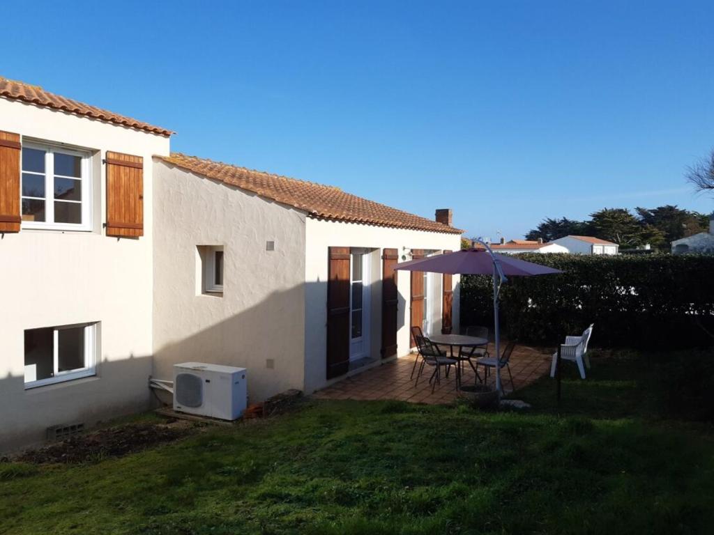 un patio avec un parasol, une table et des chaises dans l'établissement Maison spacieuse à 80m de la plage, animaux admis, WiFi gratuit - FR-1-823-19, à La Guérinière