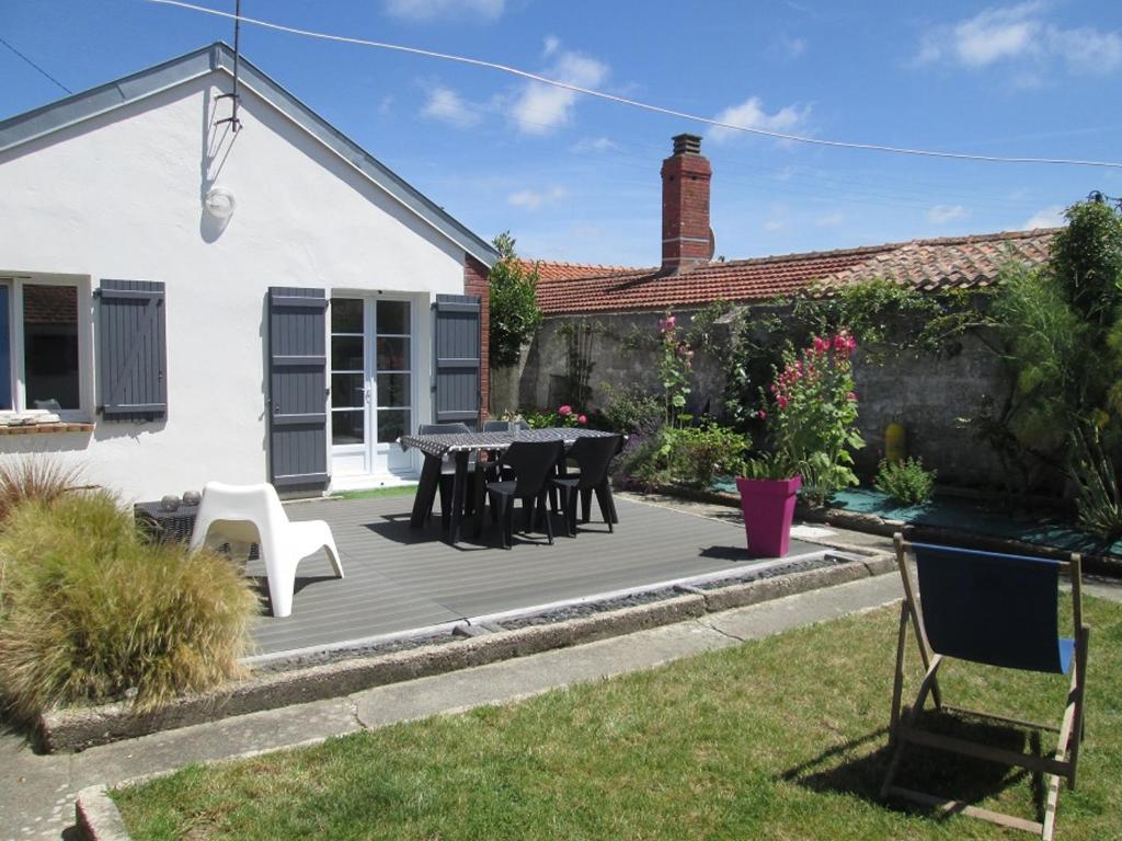 un patio avec une table et des chaises devant une maison dans l'établissement Maison à Barbâtre, proche plage, animaux admis - FR-1-823-37, à Barbâtre