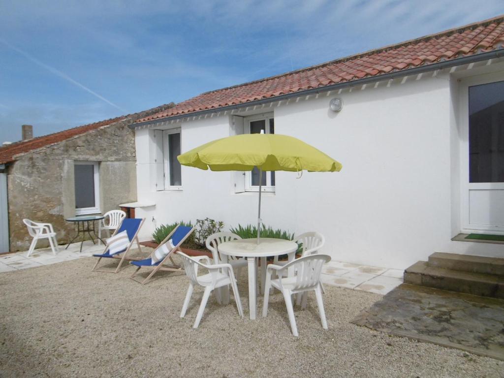 un patio avec une table, des chaises et un parasol dans l'établissement Maison cosy à Barbâtre, proche plage, jardin, 2 pers. - FR-1-823-39, à Barbâtre