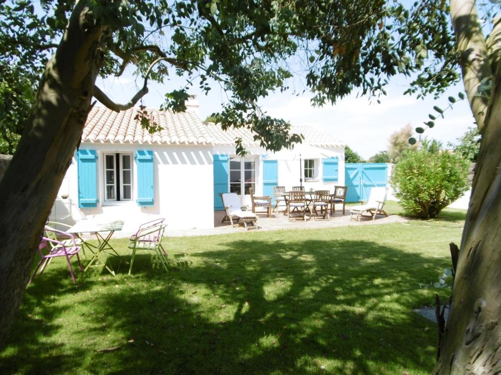 une maison bleue et blanche avec une table et des chaises dans l'établissement Maison confortable 4 pers. avec jardin fermé à L'Épine, proche plage - FR-1-823-27, à LʼÉpine