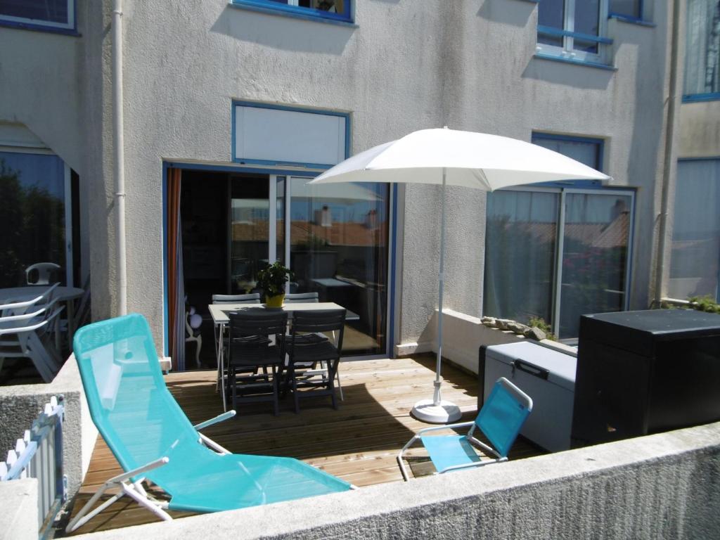 une terrasse avec des chaises, un parasol et une table dans l'établissement Rez-de-jardin 4 pers proche plage et port Noirmoutier - FR-1-823-32, à Noirmoutier-en-l'lle