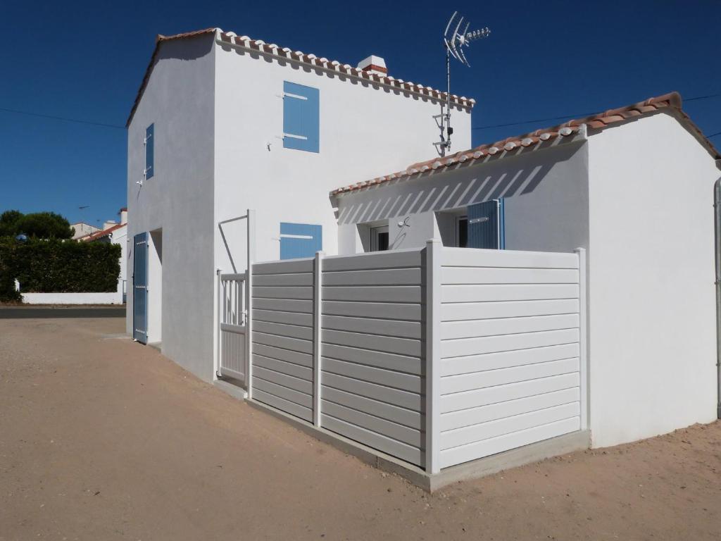 une maison blanche avec une clôture blanche dans l'établissement Maison neuve à Barbâtre, proche plage pour 2 personnes - FR-1-823-36, à Barbâtre