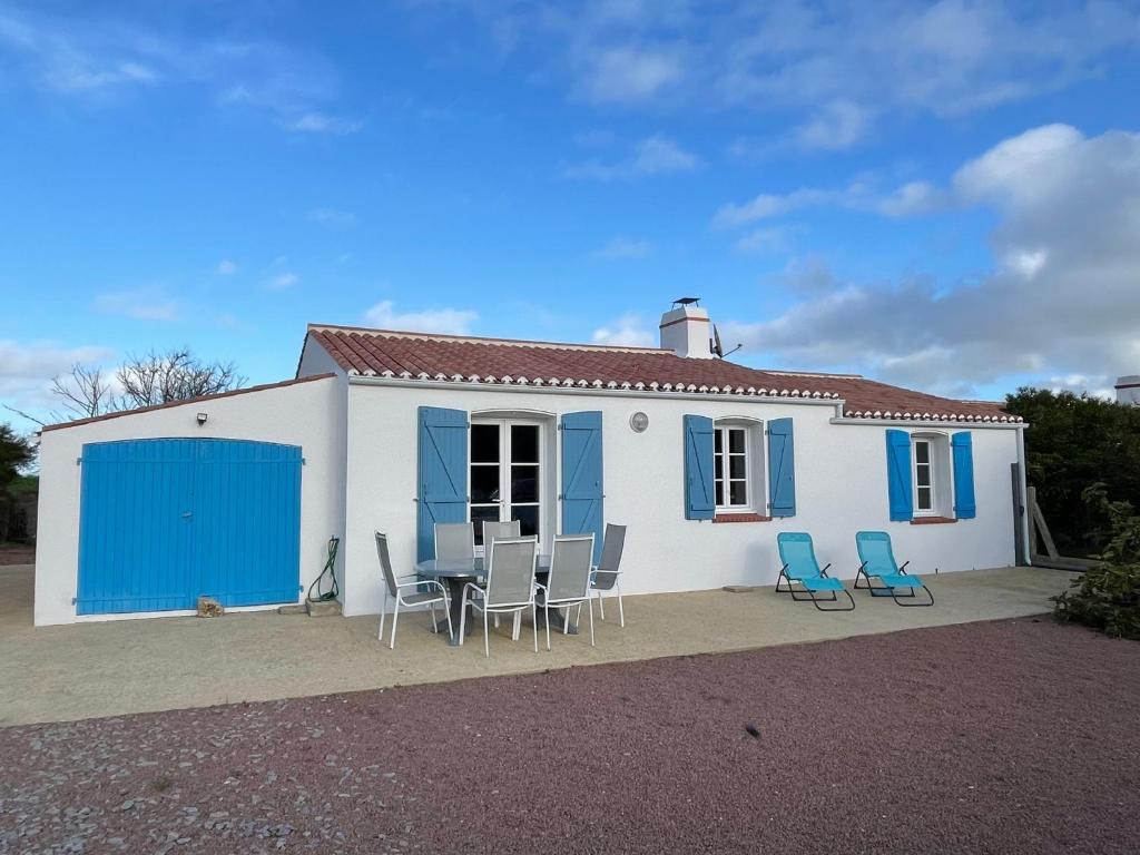 une maison avec des chaises et une table devant elle dans l'établissement Maison 5 pers à Noirmoutier, proche plage - FR-1-823-46, à Barbâtre