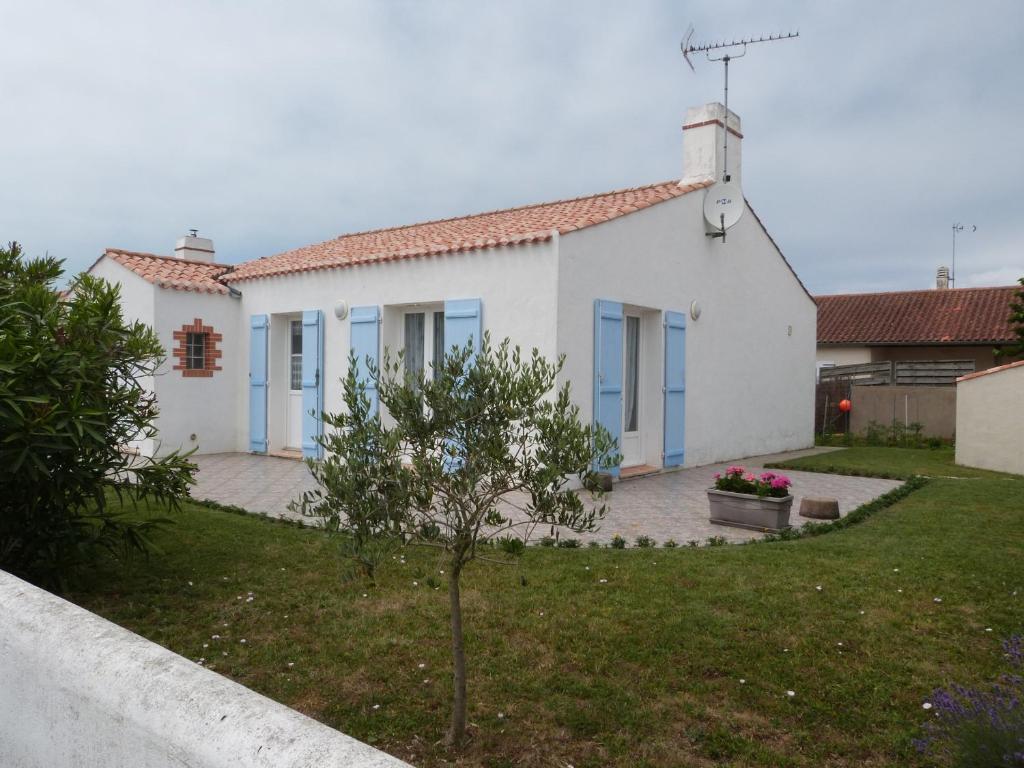 une maison blanche avec des portes bleues et une cour dans l'établissement Maison confortable à Barbâtre pour 6 pers., proche plage - FR-1-823-49, à Barbâtre