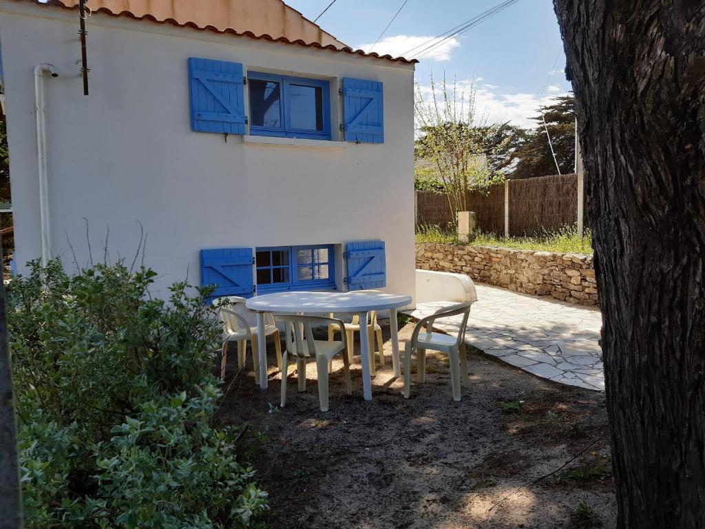 une table et des chaises devant une maison avec une fenêtre dans l'établissement Maison 6 pers, proche plage, jardin & terrasse, WiFi, Noirmoutier - FR-1-823-63, à Barbâtre