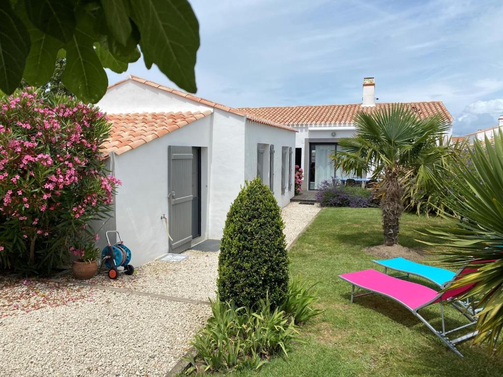 une maison blanche avec des chaises roses et bleues dans la cour dans l'établissement Maison moderne à Noirmoutier, proche plage, 6 personnes - FR-1-823-58, à Noirmoutier-en-l'lle