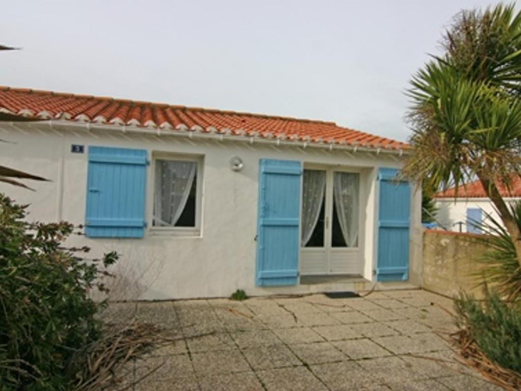 une maison avec volets bleus et palmier dans l'établissement Maison 4 Pers Noirmoutier, 300m Plage, Parking - FR-1-823-66, à Noirmoutier-en-l'lle