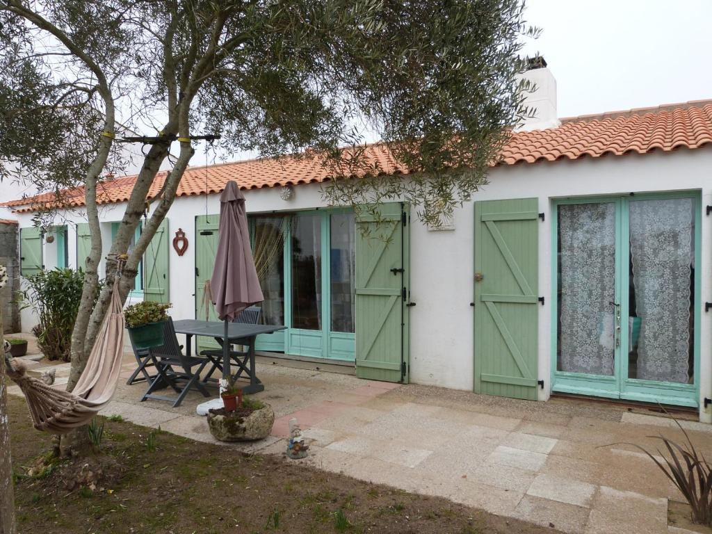 une maison avec des portes de garage vertes et une table dans l'établissement Maison en bord de mer pour 6 pers avec WIFI et animaux admis - FR-1-823-67, à Barbâtre