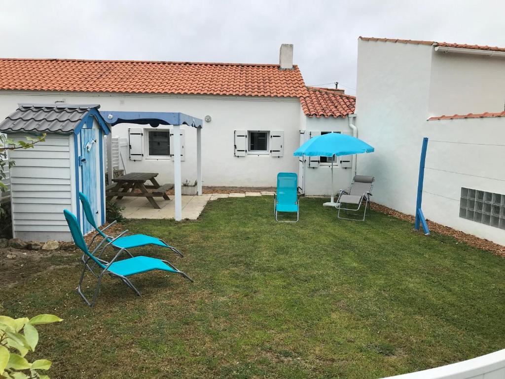 - une cour avec 2 chaises et un parasol bleu dans l'établissement Maison près des dunes, 5 min de la plage, Barbâtre - FR-1-823-79, à Barbâtre