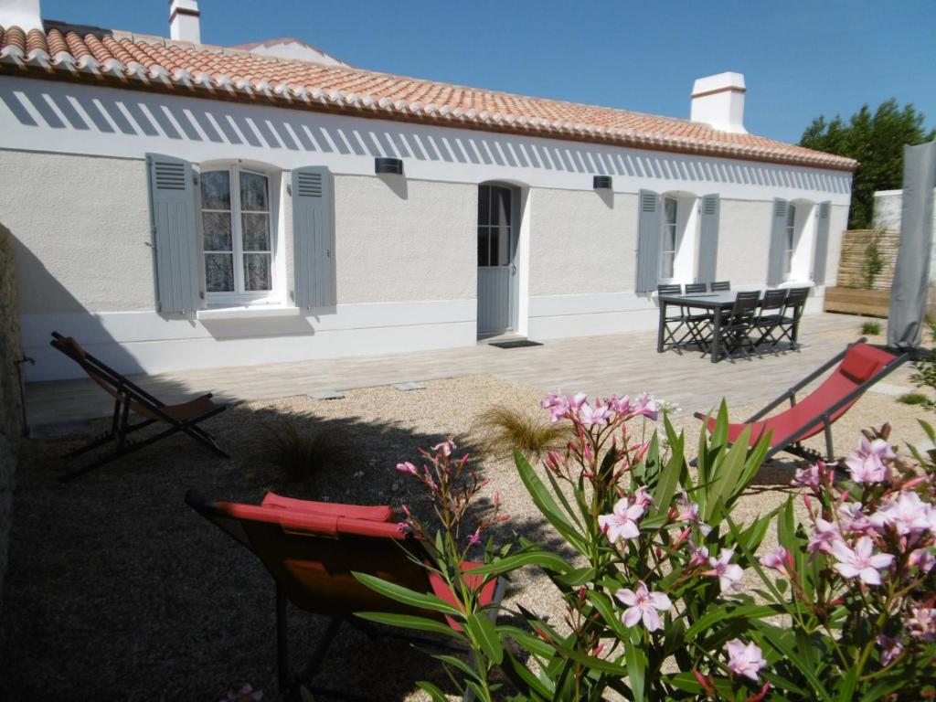 une maison avec une terrasse, un banc et des fleurs dans l'établissement Maison rénovée 2019 proche plage avec jardin privé - FR-1-823-89, à LʼÉpine