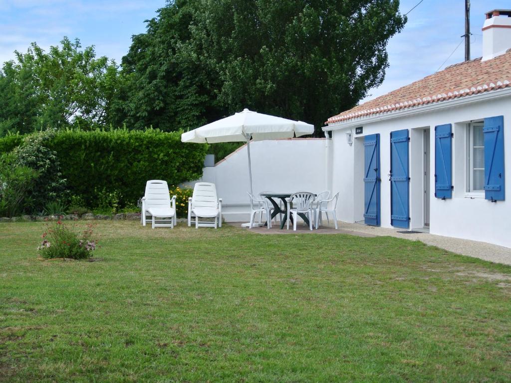un patio avec une table, des chaises et un parasol dans l'établissement Maison confortable 3 chambres proche plage à Noirmoutier - FR-1-823-95, à Barbâtre
