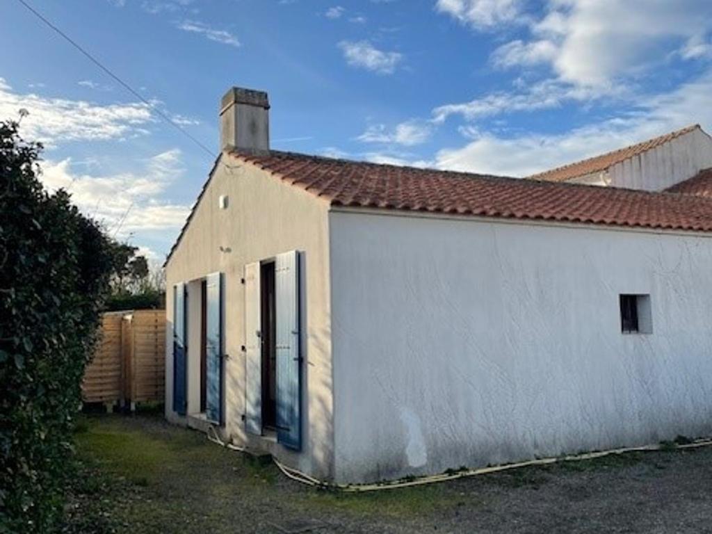 - un bâtiment blanc avec une porte dans une cour dans l'établissement Maison 4 pers à Barbâtre près plage, wifi, parking - FR-1-823-102, à Barbâtre