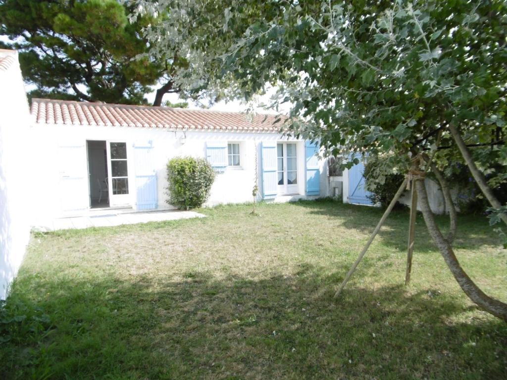une maison blanche avec un arbre dans la cour dans l'établissement Maison 2 Pers. à Noirmoutier, Proche Plage, Parking - FR-1-823-115, à Noirmoutier-en-l'lle