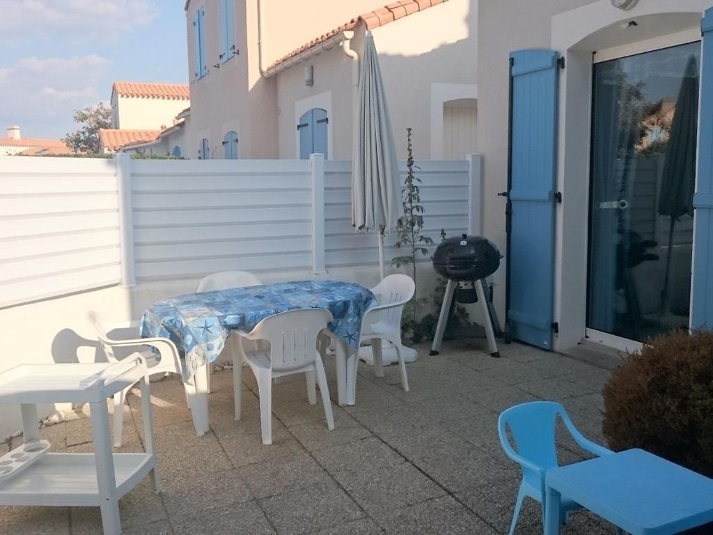 un patio avec une table, des chaises et un parasol dans l'établissement Maisonnette près de la plage pour 6 pers. - FR-1-823-119, à Barbâtre