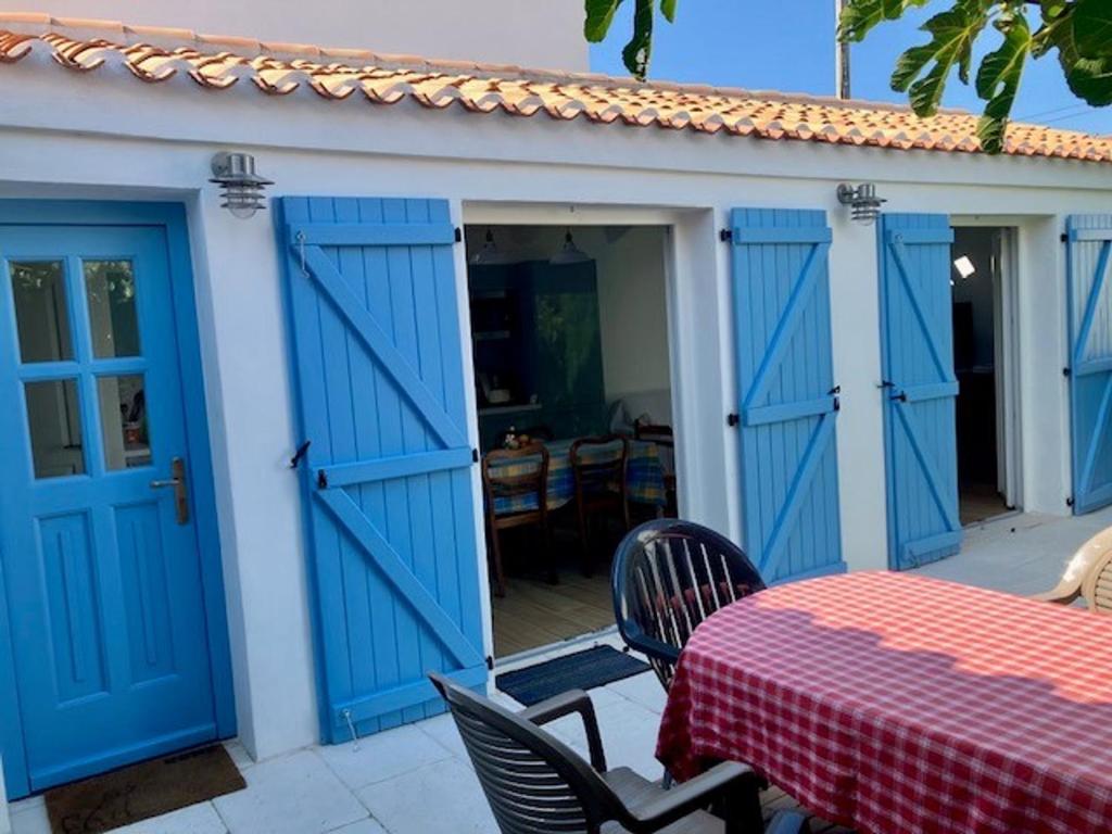 d'une terrasse avec des portes bleues et une table avec un chiffon de table. dans l'établissement Maison de plain pied à L'Herbaudière près plage et ports - 4 pers. - FR-1-823-122, à Noirmoutier-en-l'lle