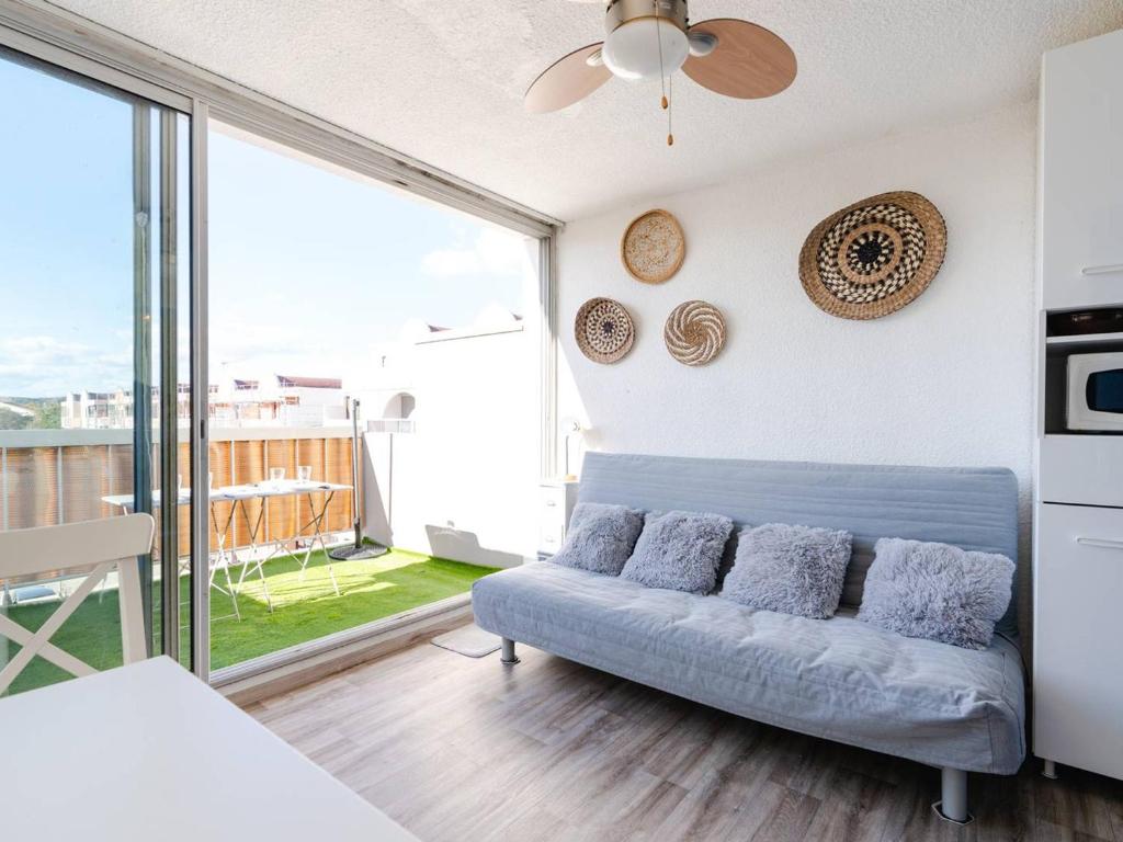 un salon avec un canapé et une grande fenêtre dans l'établissement Studio cabine avec terrasse, animaux admis, pour 4 personnes - FR-1-409A-33, à Gruissan