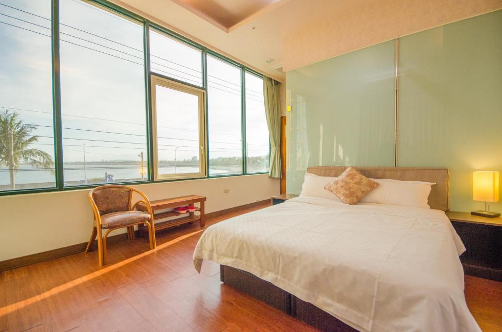 a bedroom with a bed and a desk and windows at Yenhi B&B in Taitung City