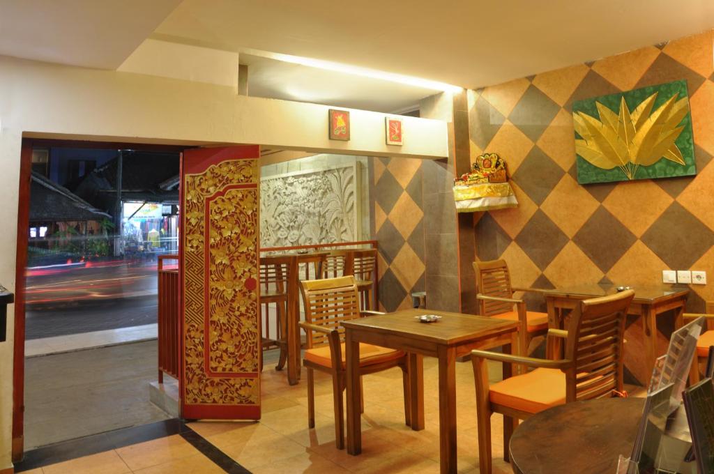 Kuta Sari House في كوتا: غرفة طعام مع طاولات وكراسي في مطعم