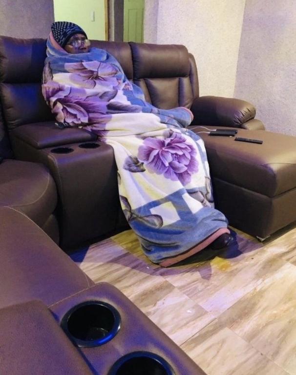 une femme qui se couche sur un canapé sous une couverture dans l'établissement Chalet bleu, à Tremblay-en-France