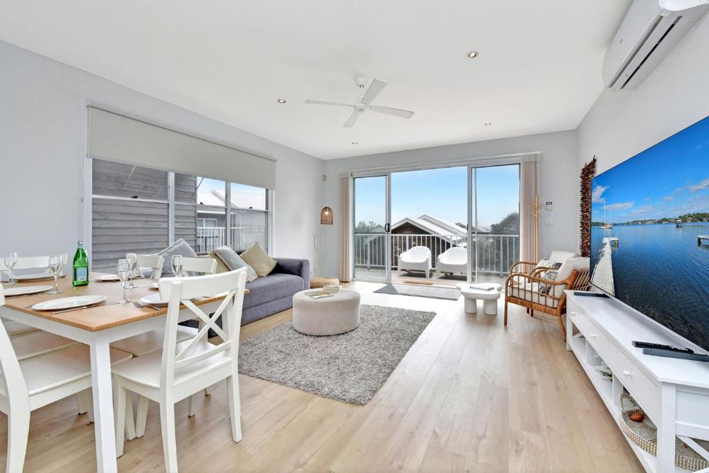 a living room with a table and a dining room with water views at Blue Lagoon at Caves Beach Villas in Caves Beach