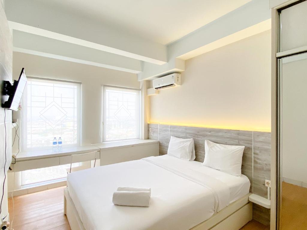 a bedroom with a white bed with a box on it at Modern Look and Comfy Studio Patraland Urbano Apartment By Travelio in Bekasi