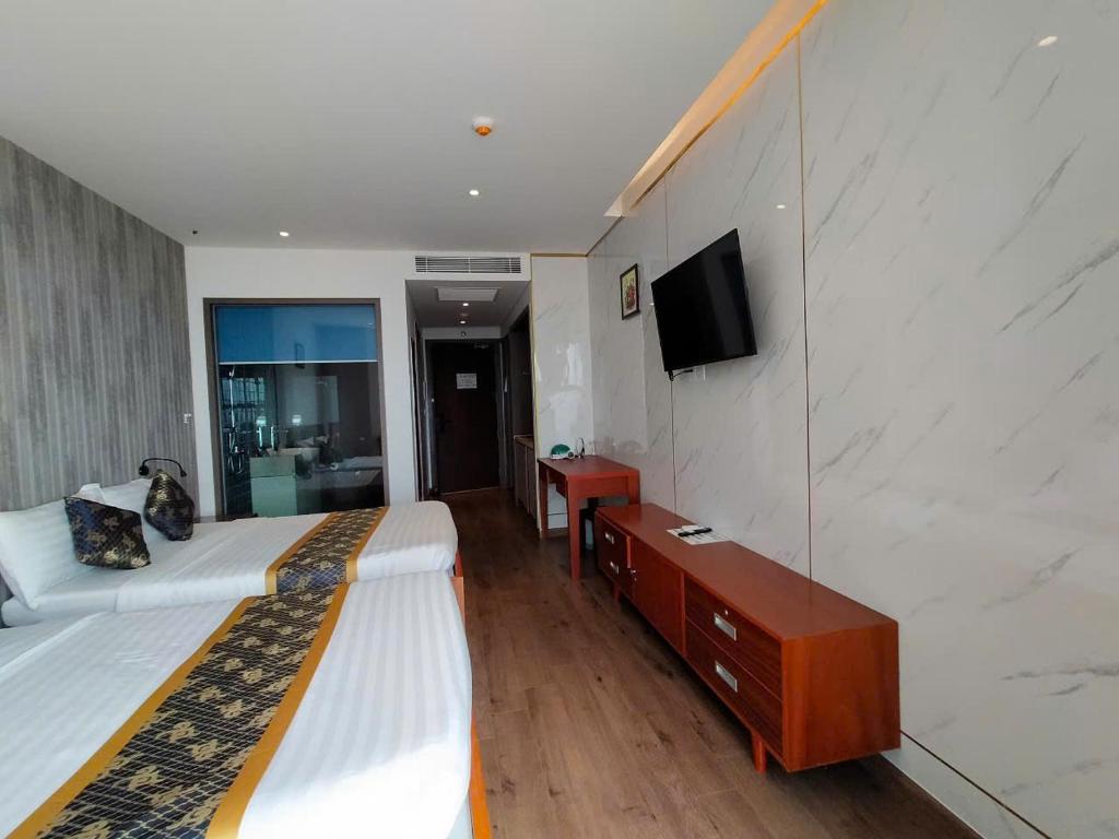 a hotel room with two beds and a tv at Chambay Bliss Retreat Mũi Né in Phan Thiet