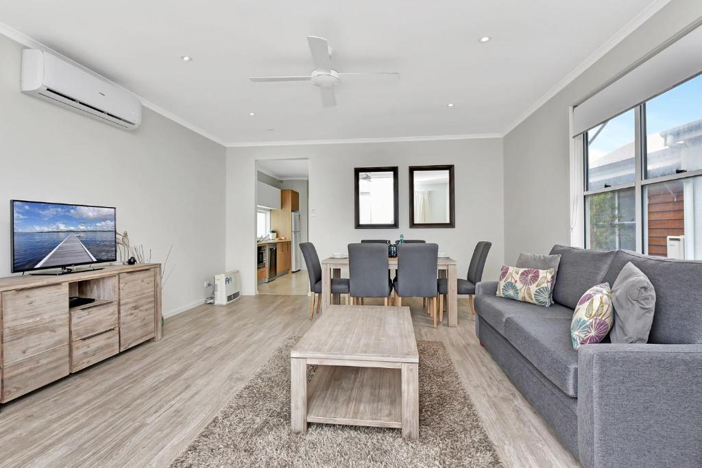 a living room with a couch and a table at Beach Escape at Caves Beach Villas in Caves Beach