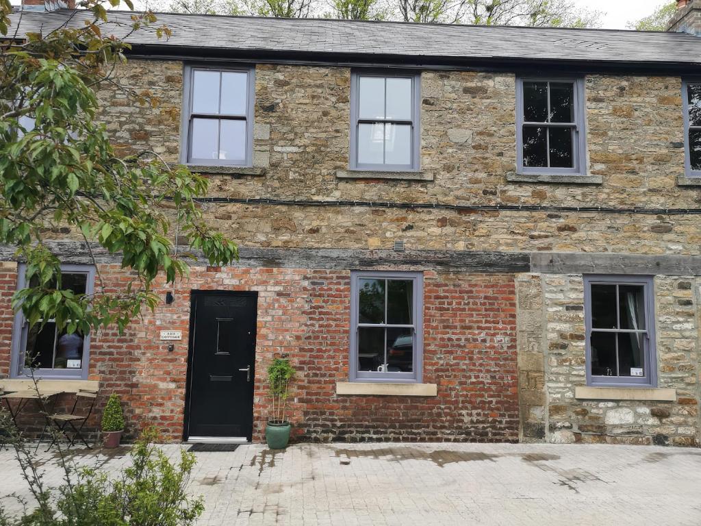 an old brick house with a black door at Ash Cottage in Barnard Castle