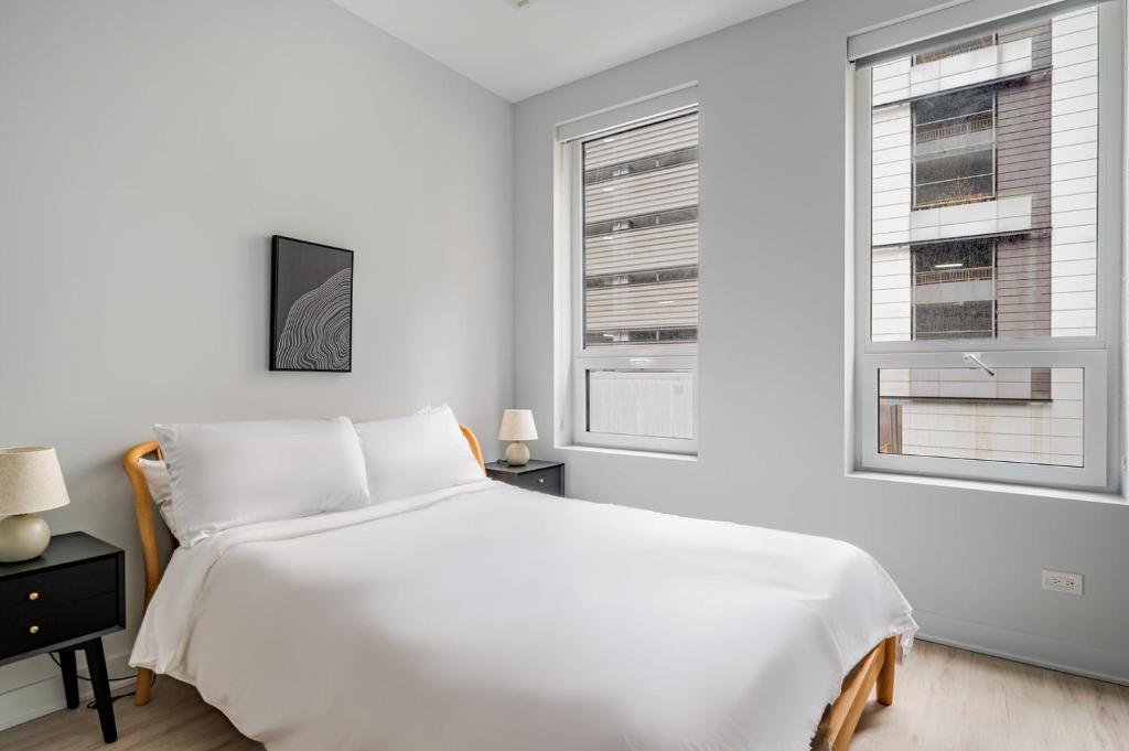 una camera da letto bianca con un letto e due finestre di Blueground The Loop elevator nr Willis Tower CHI-1236 a Chicago