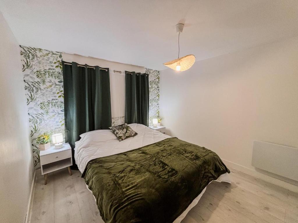 a bedroom with a large bed with green blanket at Joli T2 avec wifi et Netflix proche du golf in Bellême